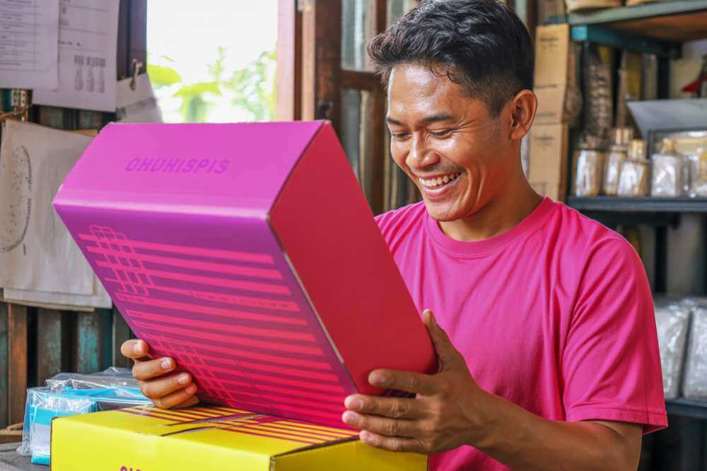 Pebisnis Menerima Paket Produk Dengan Kemasan Custom Dari Layanan Print On Demand Lokal Di Indonesia.