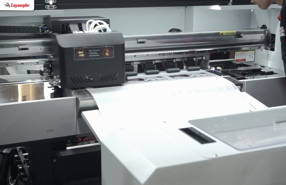 Mesin Printer Dtf Sedang Beroperasi Mencetak Desain Pada Media Film Sebagai Peralatan Utama Dalam Bisnis Sablon Dtf.