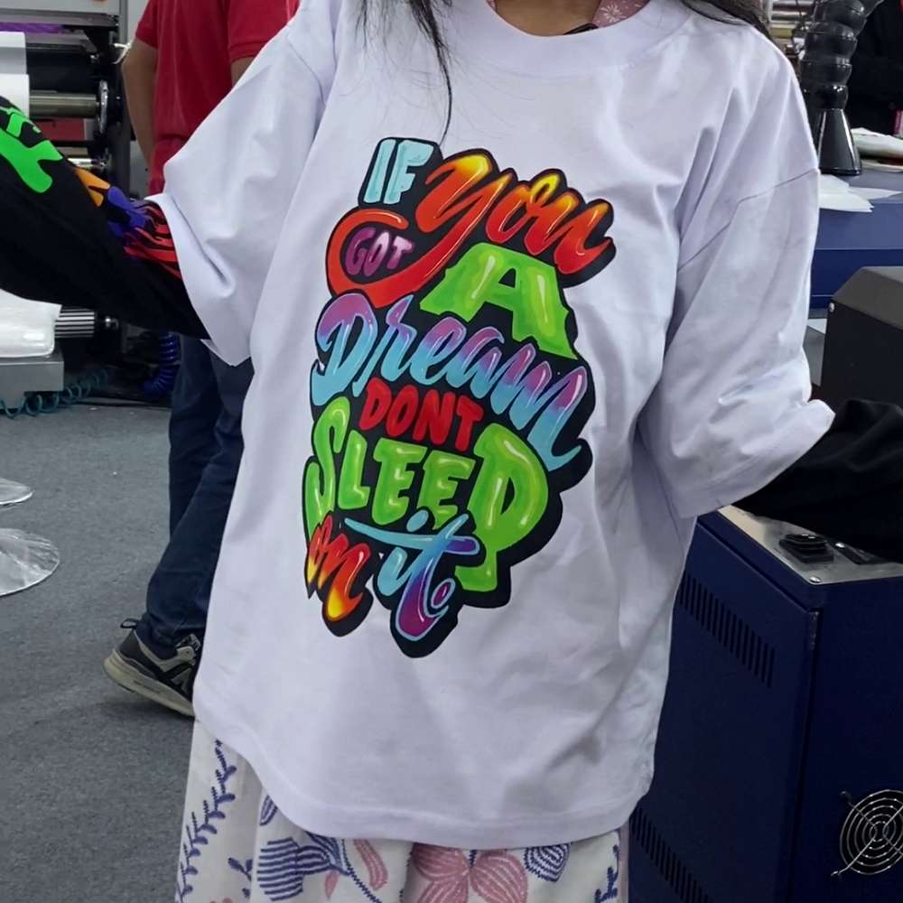 Kaos Putih Dengan Hasil Sablon Dtf Penuh Warna Setelah Melalui Tahap Finishing Post-Press.