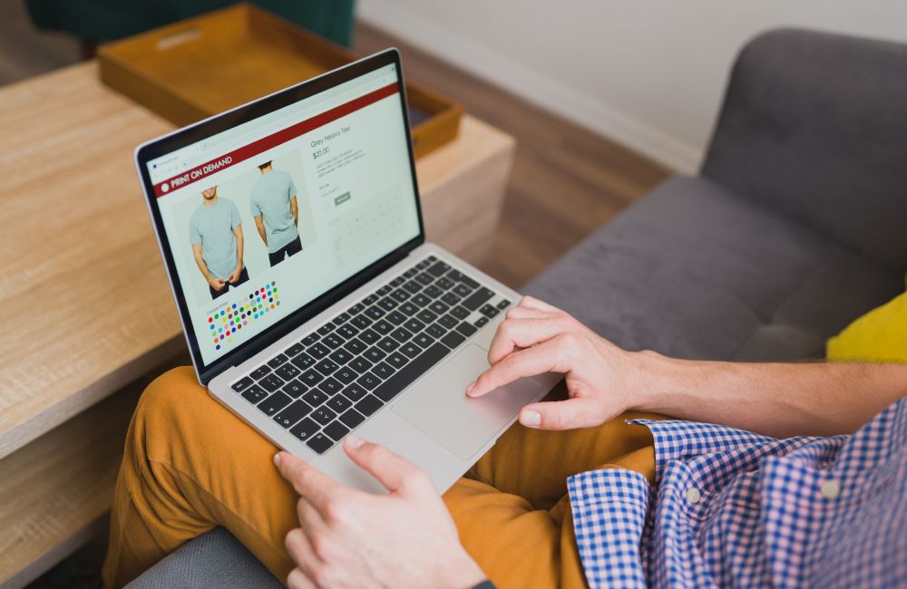 Seseorang Membuka Laptop Untuk Membuat Toko Online Produk Kaos Custom Di Platform Internasional.